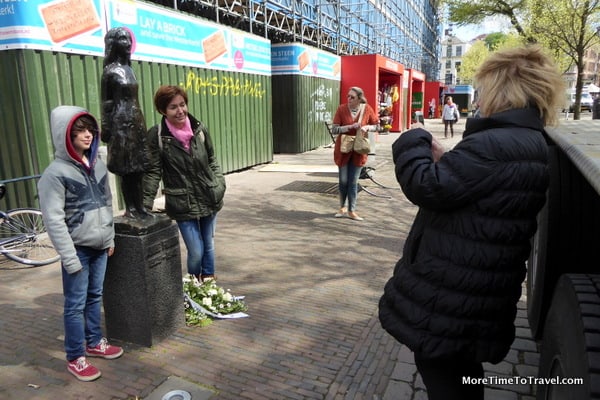 A mother poses with her daughter beside a statue of Anne Frank