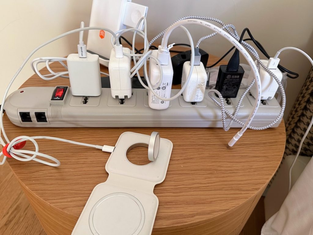 Cables for multiple electronic gadgets on a hotel night table (credit: Jerome Levine)